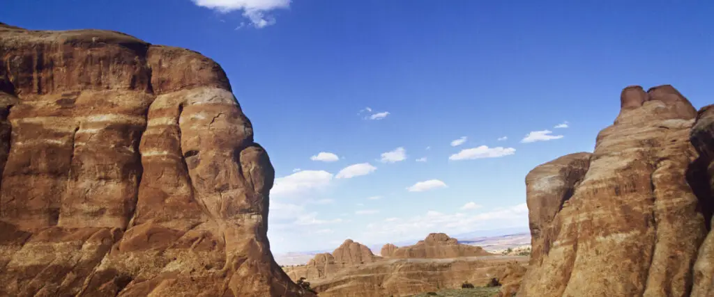 Rock formations under a blue sky with scattered clouds at Arches National Park invite visitors to explore the breathtaking beauty of our national parks. Take advantage of free entrance days in 2022 to experience this natural wonder firsthand.