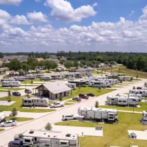 Aerial view of Rayford Crossing RV park, showcasing numerous parked RVs, a central building, and lush green spaces under a cloudy sky.
