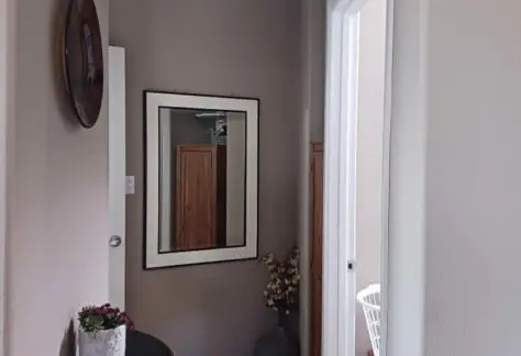 The hallway of the 2010 Chariot Eagle mobile home features a mirror on the wall, a side table adorned with lush plants, and doorways leading to other inviting rooms.