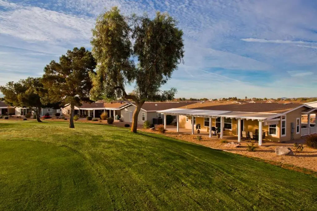 Picture yourself in a row of houses with covered patios, facing a well-maintained green lawn and trees under the year-round blue skies of Arizona.