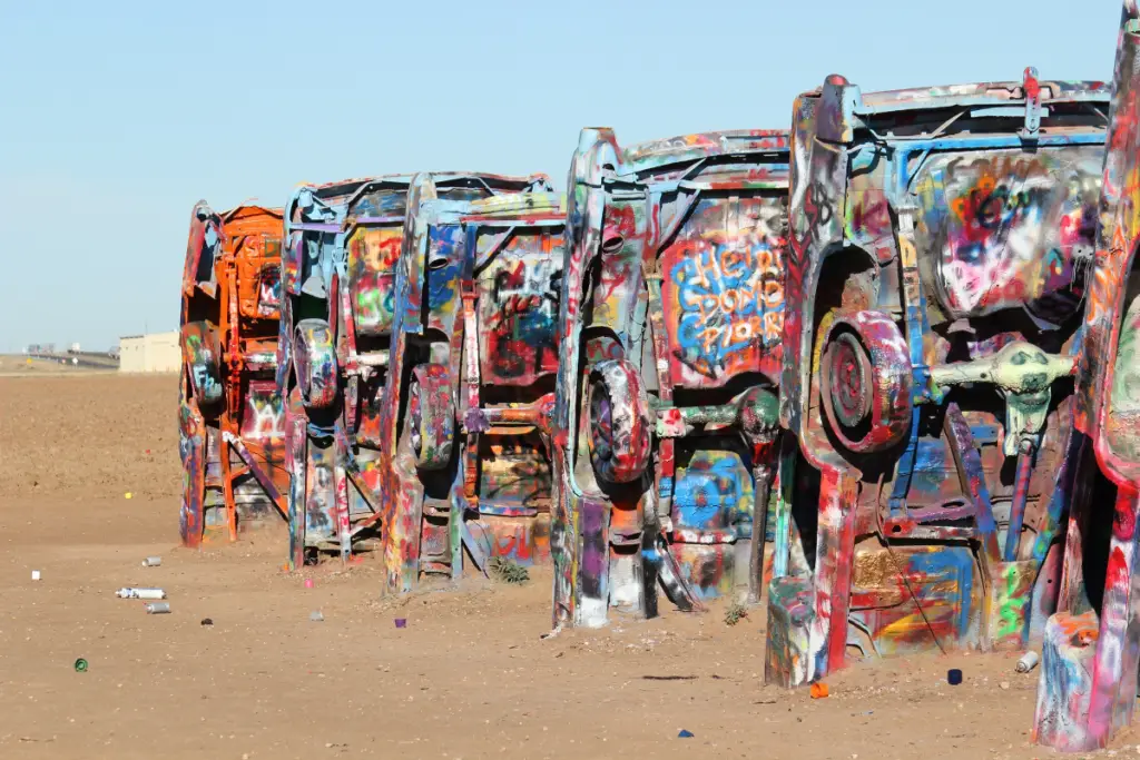 In Amarillo, discover a row of half-buried, vividly graffitied cars in a barren landscape under a clear blue sky, one of the city's unique cultural gems perfect for outdoor adventures.