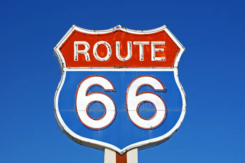A Route 66 road sign with a red and blue design stands against a clear blue sky, marking the start of spring adventures in Amarillo.