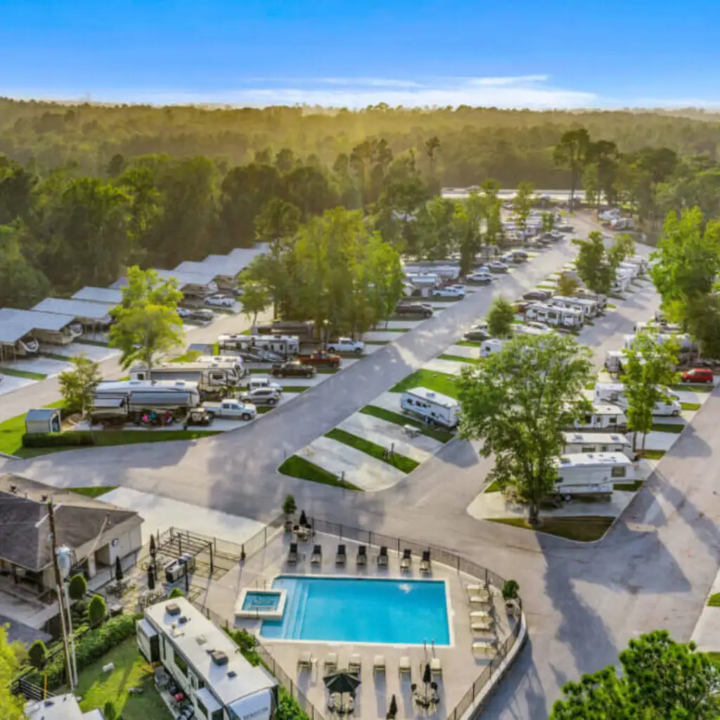Aerial view of an RV park near Lake Conroe, featuring numerous trailers, a swimming pool, and tree-lined roads. Perfect for those visiting Texas Winter Events or exploring the charm of Willis, Texas.