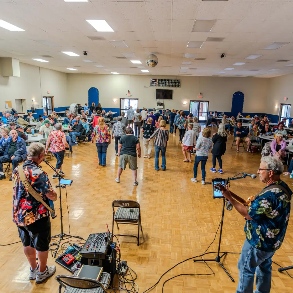 In January, a lively band performs at a large community hall, where residents of Sunrise RV Resort enjoy various activities, dancing joyfully while others relax at the tables.