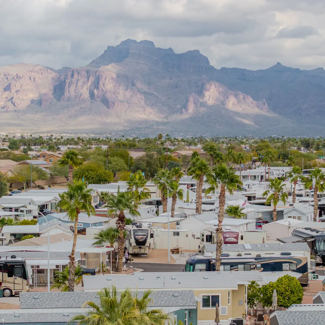 Sunrise RV Resort, nestled amidst palm trees with a stunning mountain range as its backdrop, offers an idyllic scene under a cloudy sky. Perfect for January getaways, it boasts numerous activities for all to enjoy.