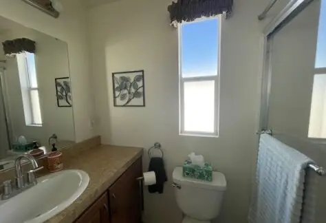 Located at Lot 430, this inviting bathroom features a sink, countertop, toilet, and bath with shower. A large wall mirror complements the bright window beside it, while elegant wall art adds charm. Crafted by Cavco in 2013, this space blends function and style effortlessly.