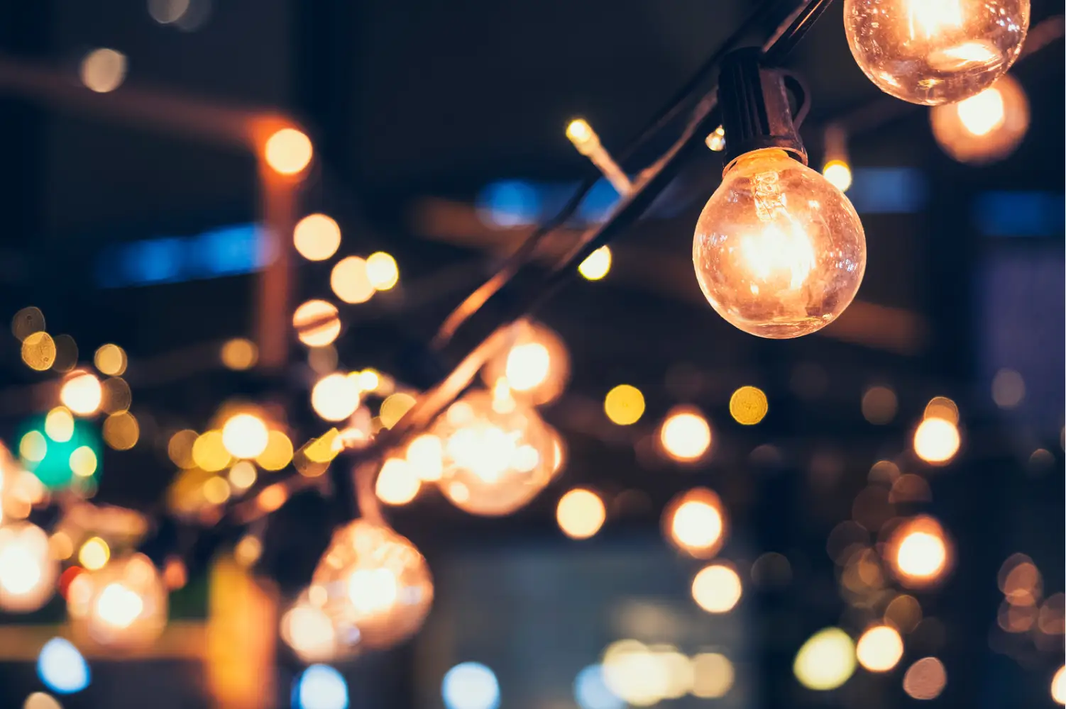 A close-up of glowing string lights with round bulbs casts a warm and festive ambiance, perfect for celebrating Thanksgiving at a cozy lakeside retreat.