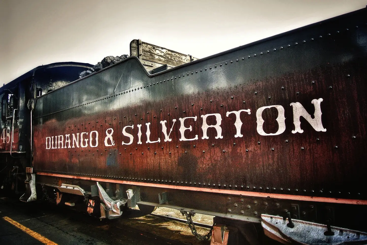A close-up of a rusted train car with the text "Durango & Silverton" on its side, evoking the charm of a cozy winter stay reminiscent of an Durango during the holidays.