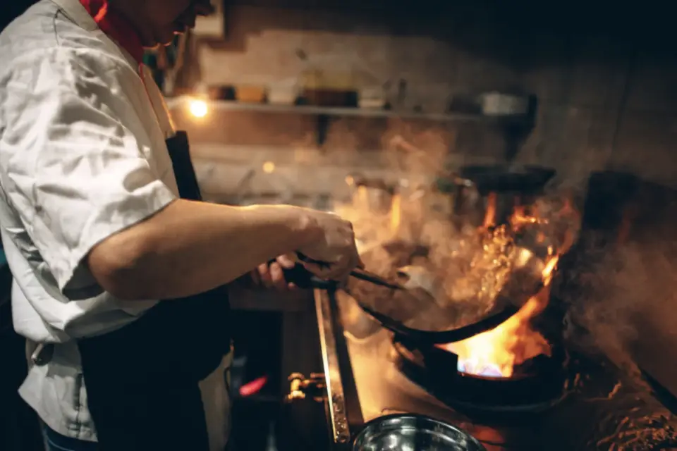 In the cultural gem of Downtown Durango, a chef skillfully maneuvers a wok over a high flame, with steam and flames dancing in harmony.