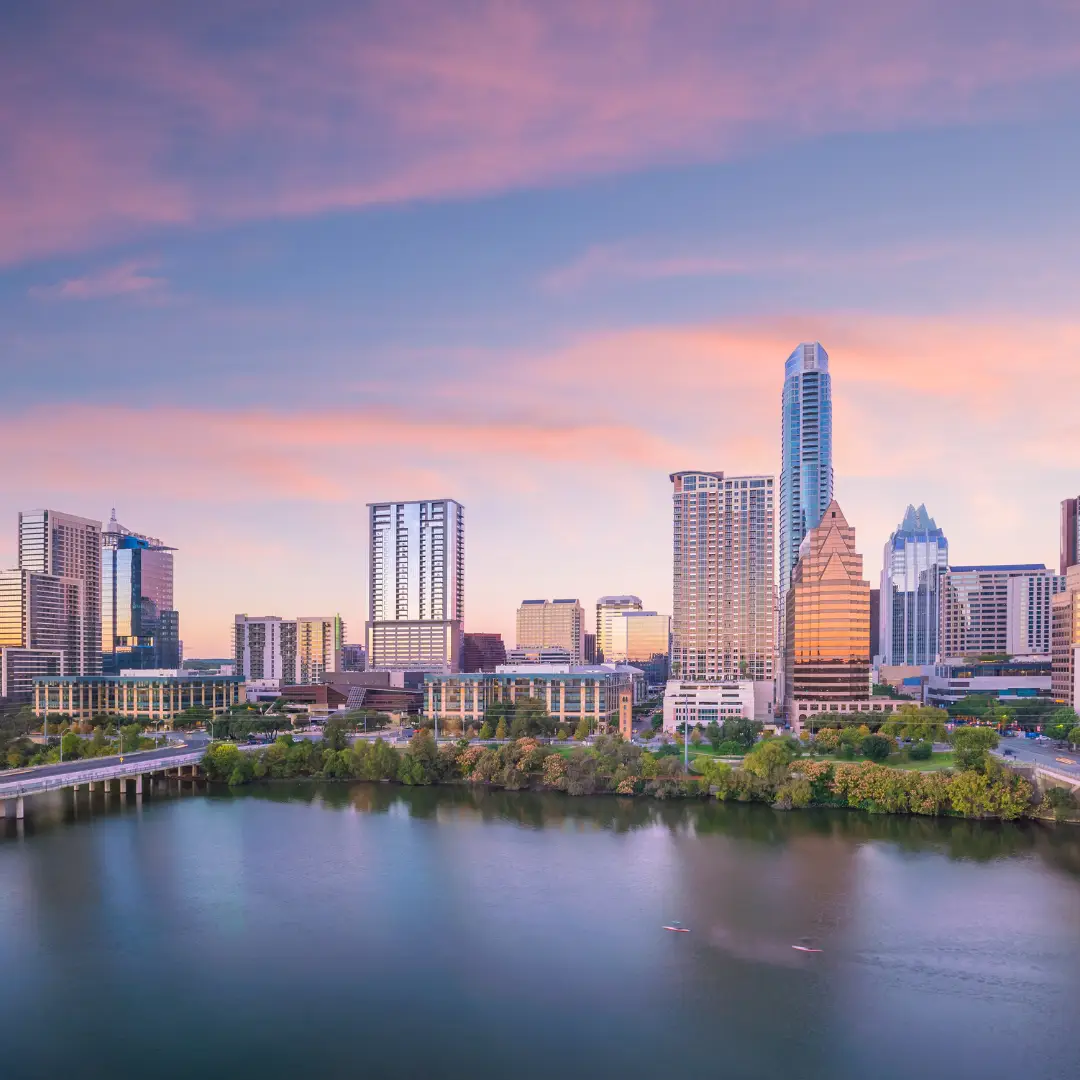 A city skyline at sunset with tall buildings and a river in the foreground evokes the charm of Austin. The sky is pink and blue with scattered clouds, hinting at the promise of upcoming events for Spring 2025.