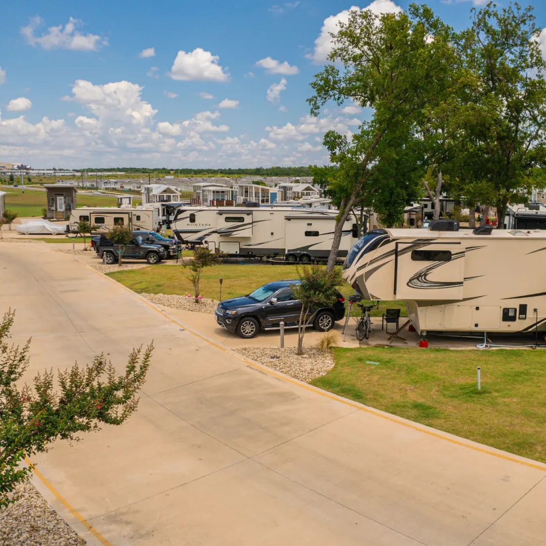 Nestled in vibrant Austin, this RV park features several motorhomes and cars basking under the partly cloudy, sun-kissed skies of Summer 2025. Surrounded by lush grass and trees, it's the perfect spot to enjoy upcoming events amidst nature's tranquility.