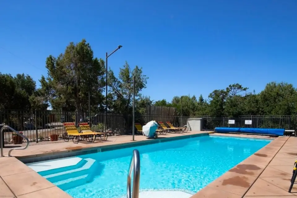 The Oasis Durango Resort features a stunning outdoor swimming pool, surrounded by lounge chairs and trees, creating the perfect retreat on a clear day.