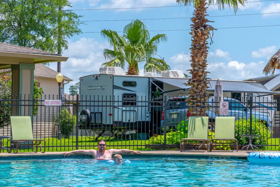 A man swims in a pool, with a camper van and palm trees in the background, capturing a serene moment that feels perfect for Valentine's Day romance.
