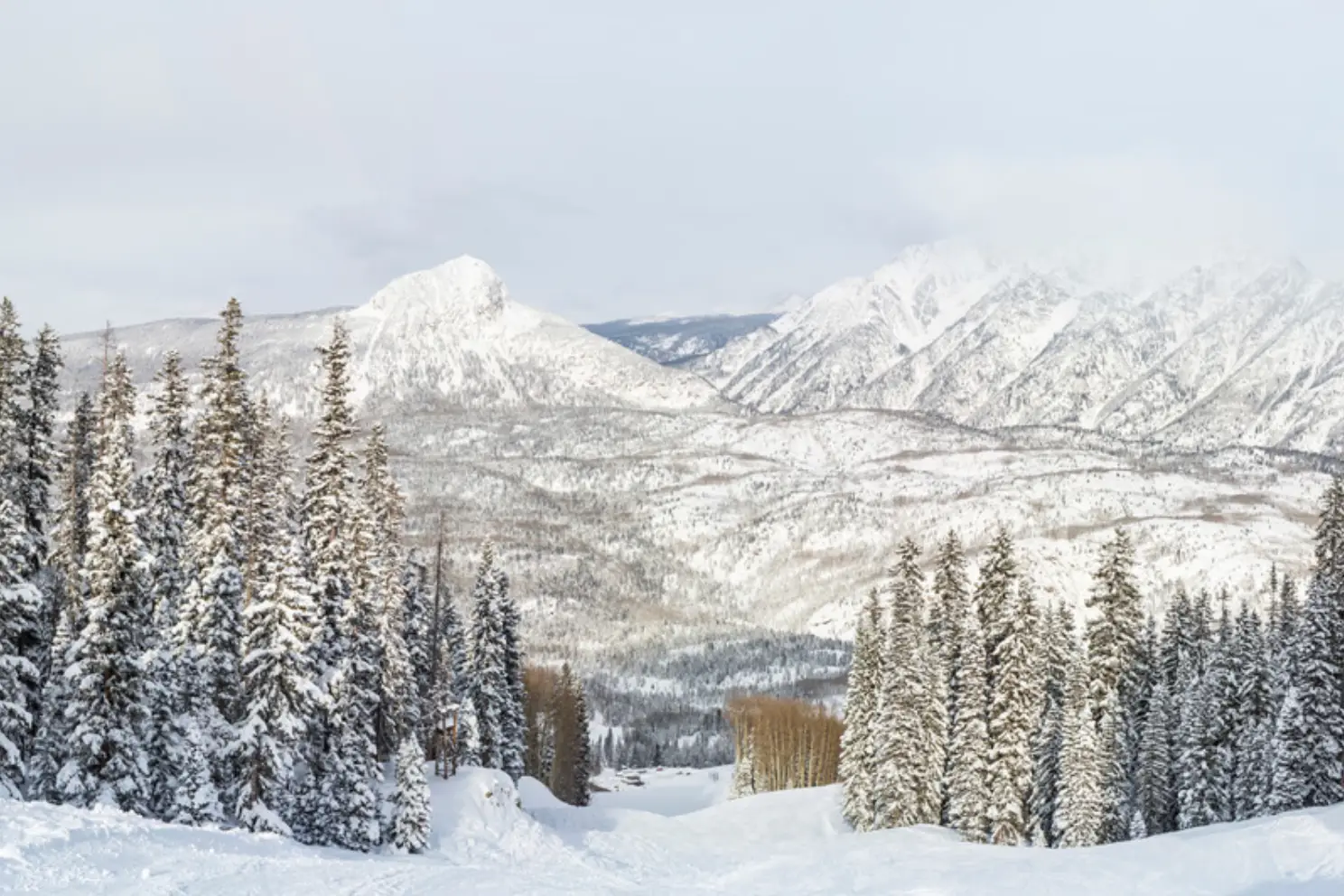The off-season reveals a snow-covered landscape with pine trees and mountains under a cloudy sky, perfect for a winter RV escape in Durango.
